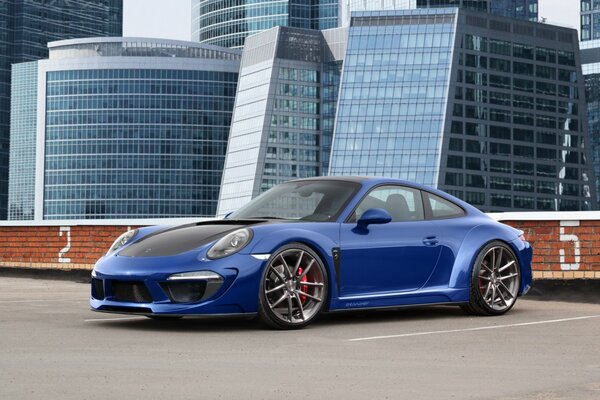 Der blaue Porshe Carrera 911 Stinger steht im Obergeschoss eines mehrstufigen Parkplatzes mit Blick auf die Linse