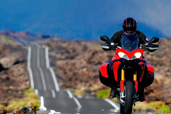 Un homme conduit sur une Ducati rouge sur une route de montagne