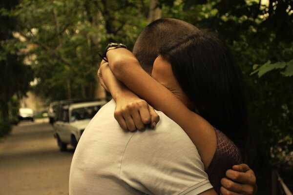 A woman and a man hug tightly among the trees