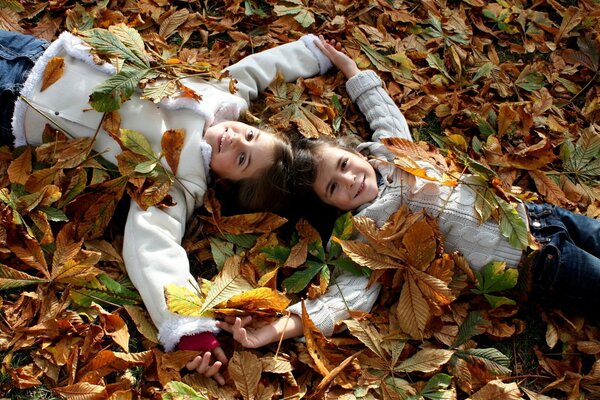 Two girls in autumn leaves