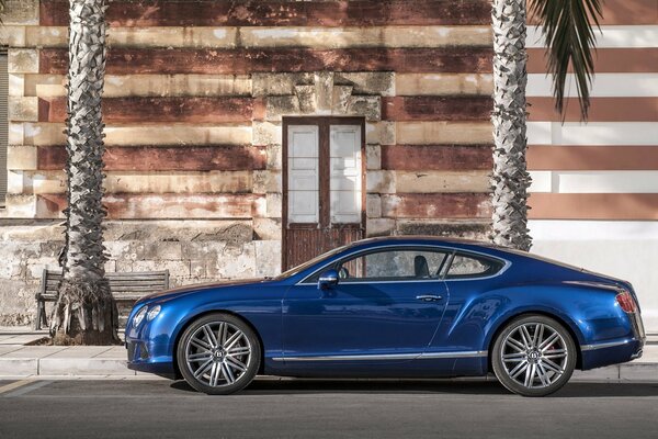 Une voiture bentley de couleur bleue garée près d un bâtiment