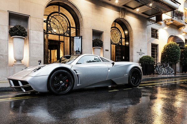 Картинка белого припаркованного у здания авто pagani huayra