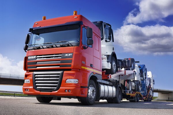 A truck carries trucks under a clear sky