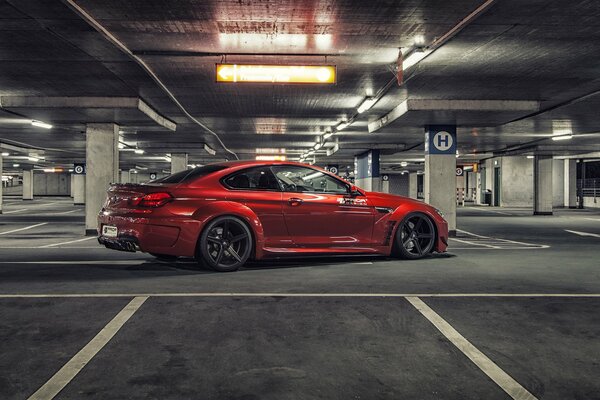 Czerwone bmw M6 na parkingu z boku