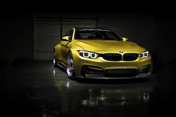 A gold-colored BMW stands full-face in complete darkness