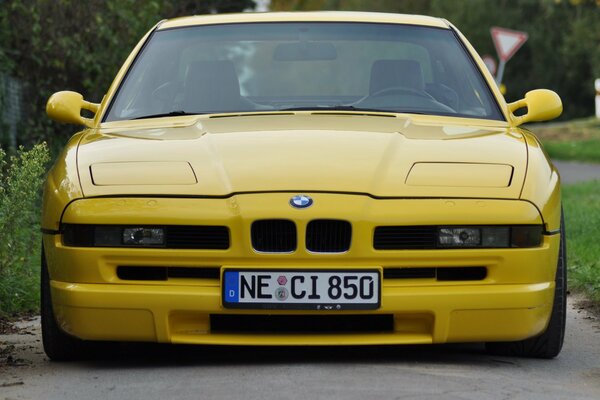 Coche amarillo en la carretera cerca de la vegetación