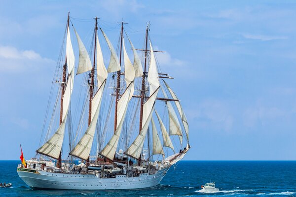 A white sailboat and a small boat at sea