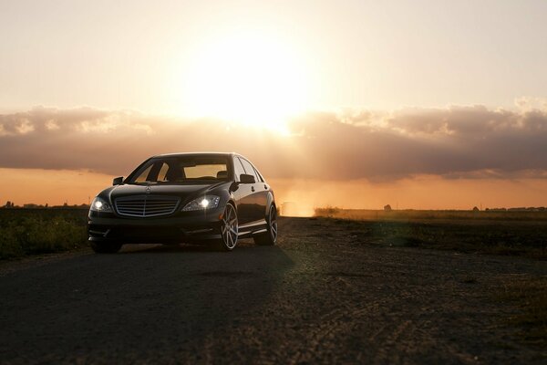 Un Mercedes austero en medio de las nubes y la puesta de sol en el campo