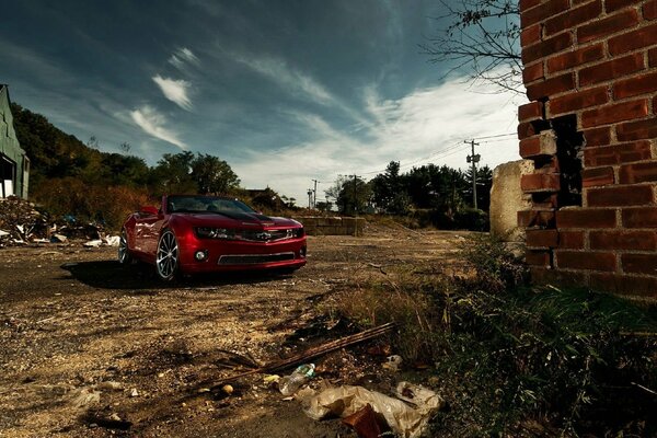 Red convertible and red bricks on a background of clouds