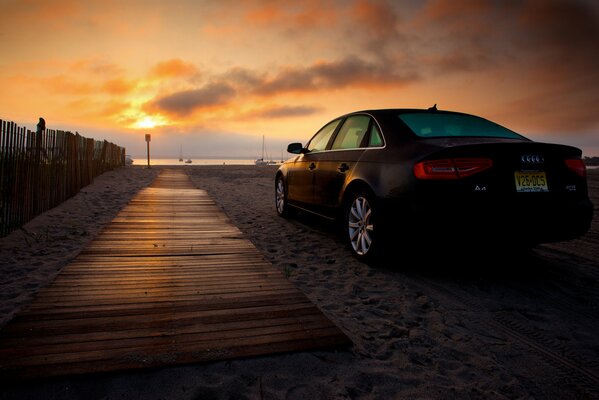 Amanecer en la playa y coche de pie en la arena