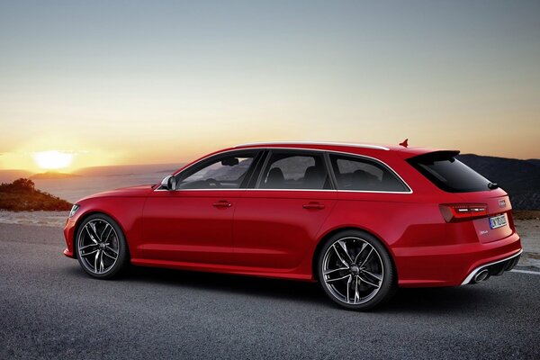 Rojo Audi vagón en el fondo de la puesta de sol en la carretera