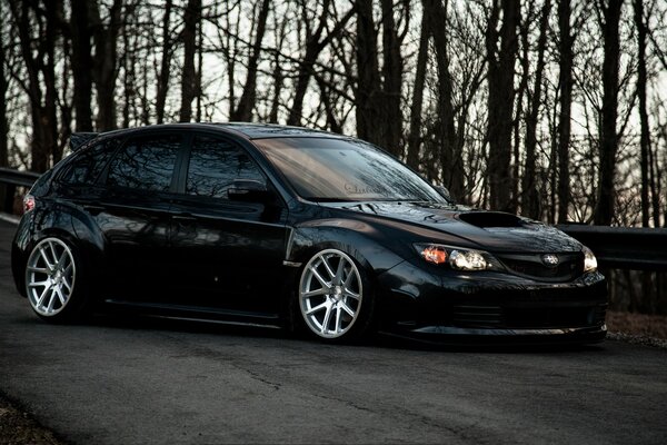 Black subaru impreza on a background of trees