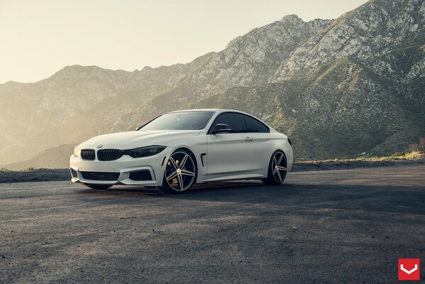 Voiture blanche de marque bmw sur fond de montagnes et de l aube