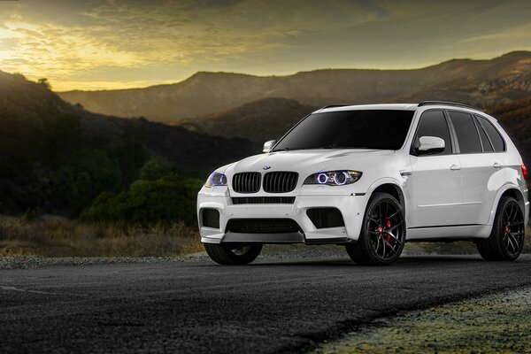 White bmw will drive along the road along the mountains