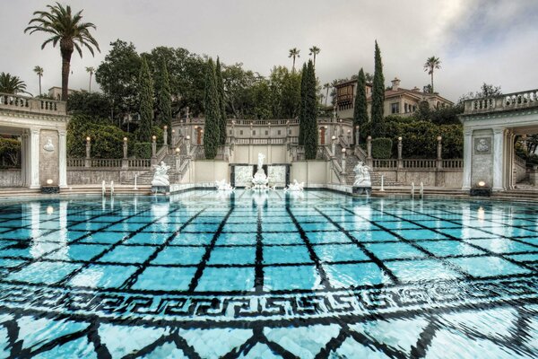 Piscina azul en el parque del Resort con escaleras y cipreses