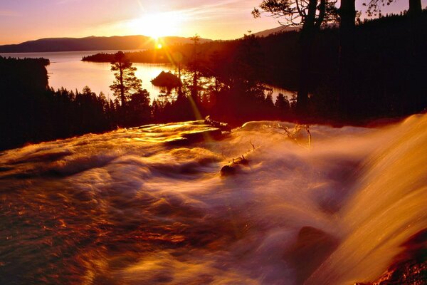 The spray of the waterfall reflects the rays of the sun