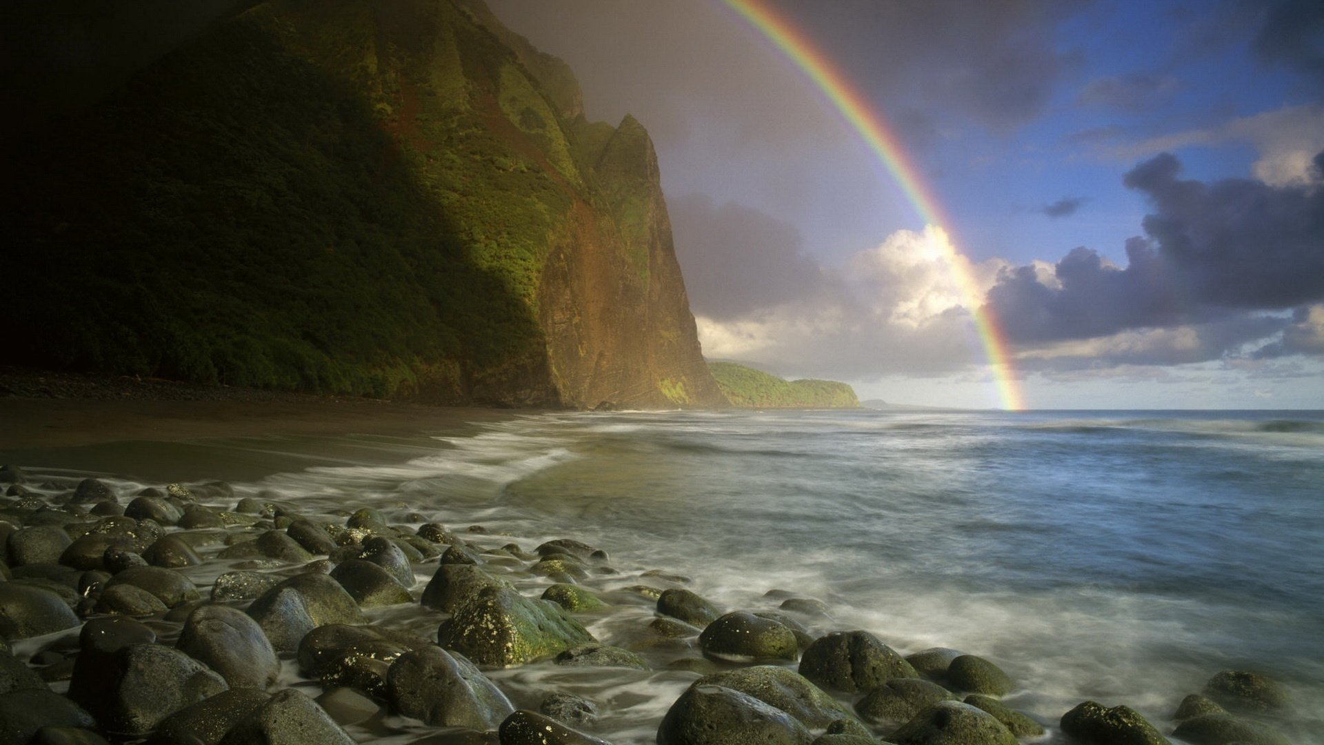 arco iris montañas verdes guijarros agua mar surf costa cielo nubes