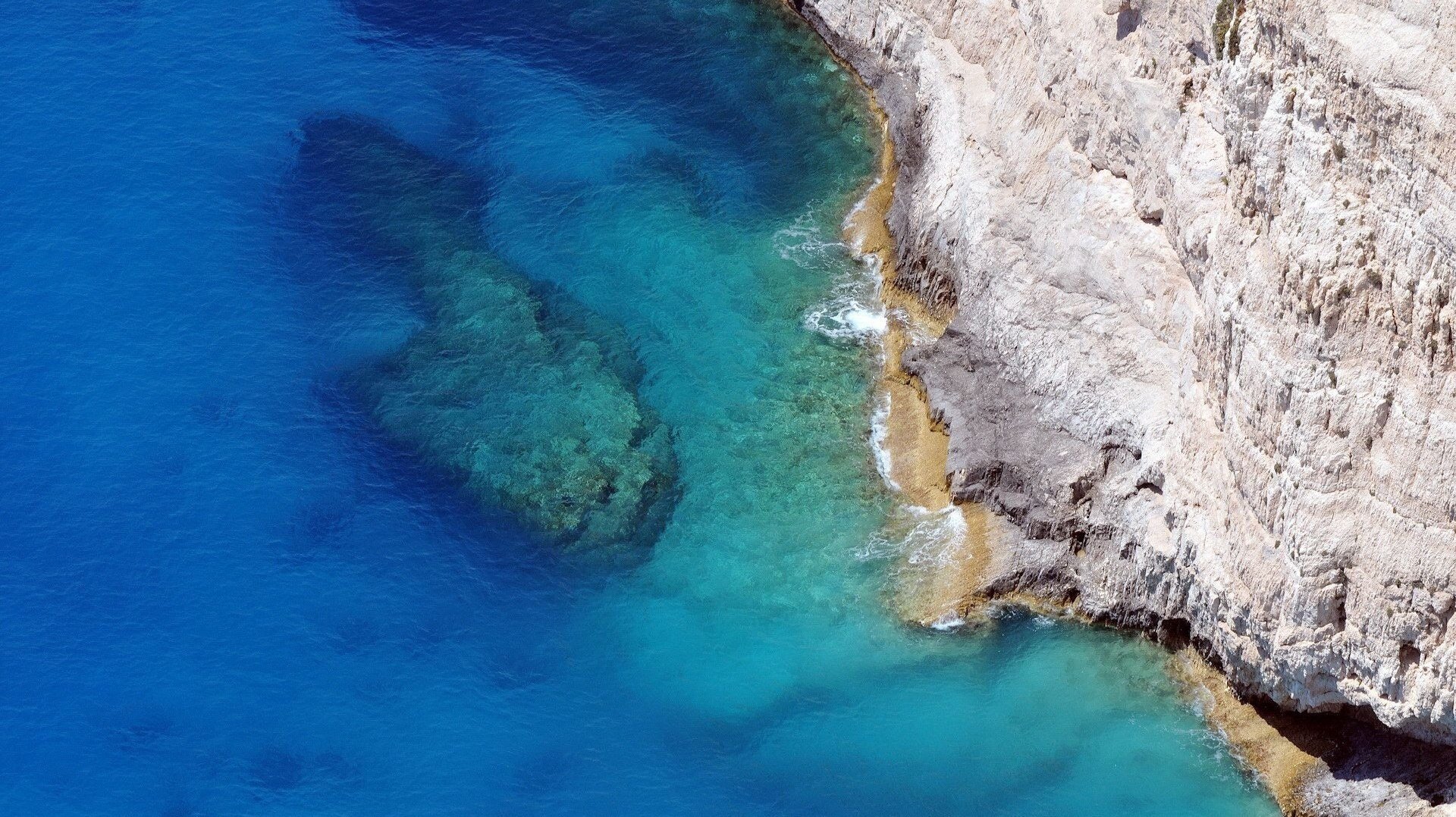 a steep cliff open stone rock blue water height sea the bottom surf shore surface nature view island stone