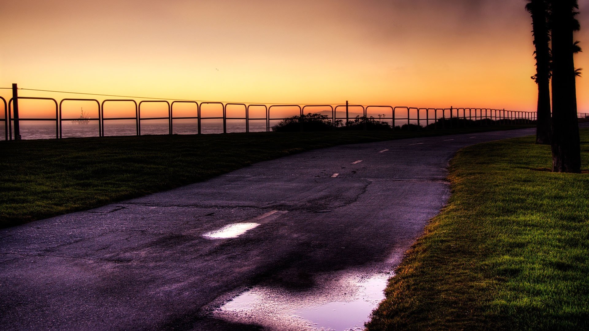 zaun am wasser straße nasser asphalt sonnenuntergang