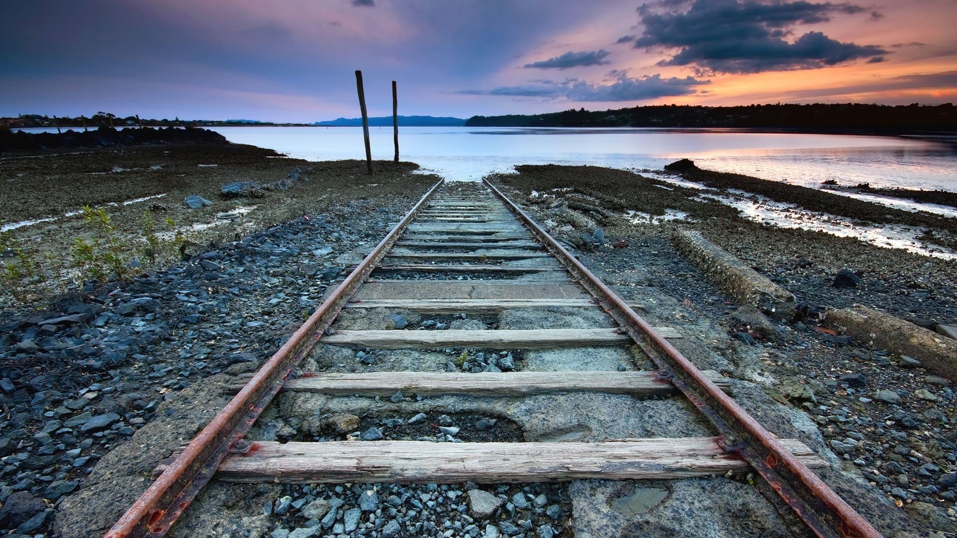 goes into the water road to nowhere railroad stones road sunset rails horizon the evening lake clouds rust