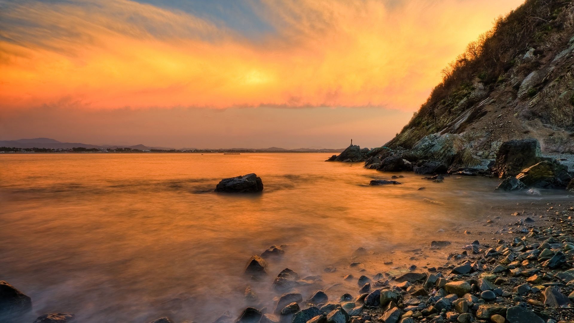 orange sky small stones the mist over the water sunset water the sky stones the evening nature landscape haze hill