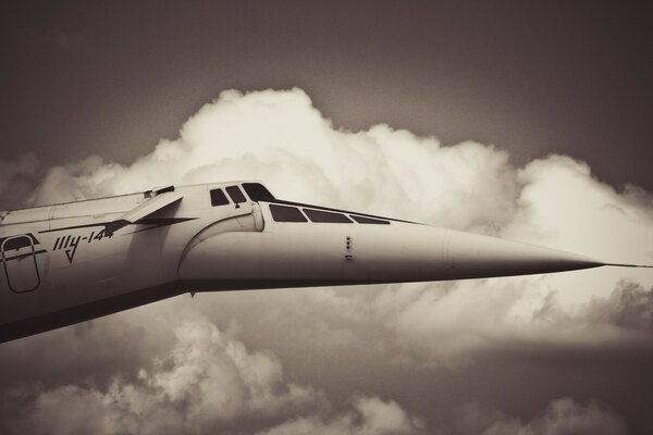 A plane with a sharp nose flies in the clouds