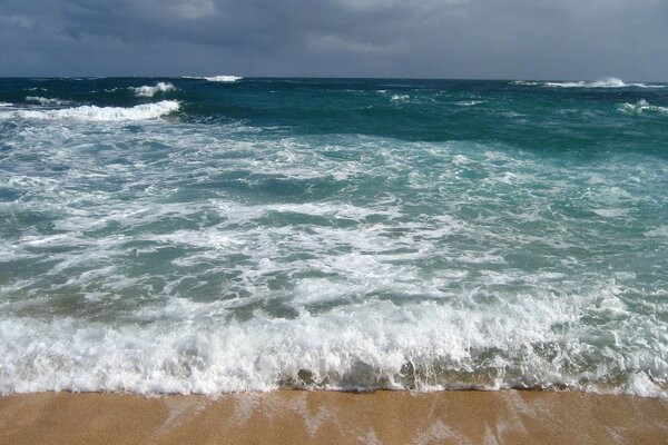 An impending wave on a sandy beach