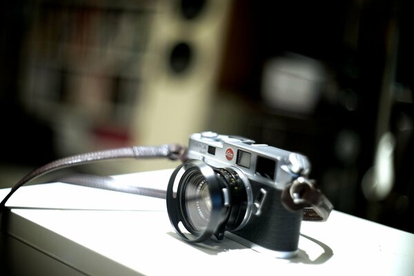 Black and silver camera with a tie on a white surface