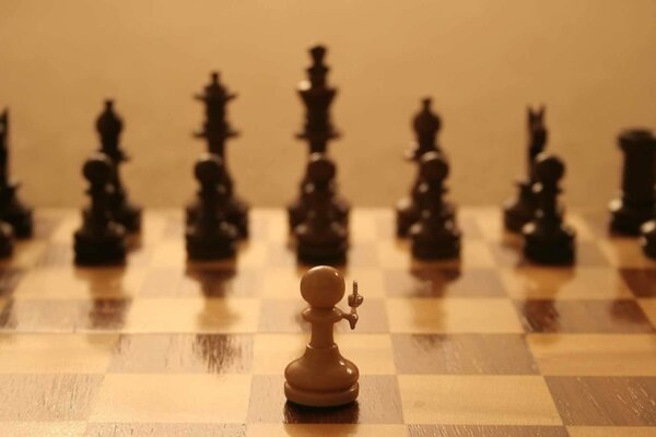 White pawn on the chessboard against black chess pieces