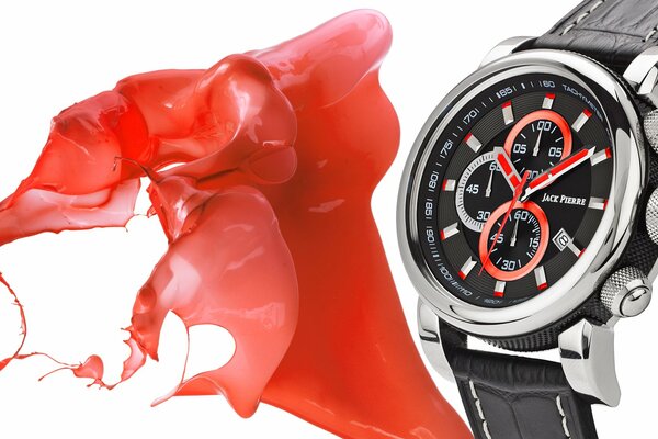 A watch with a metal case and a leather strap on a background of red splashes