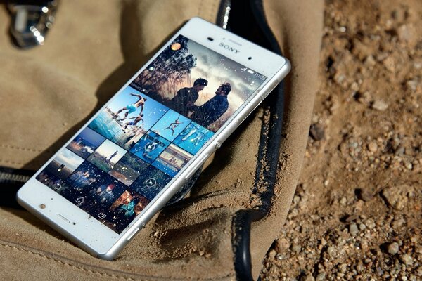 Sony s smartphone is lying on a backpack that lies on an earthy surface