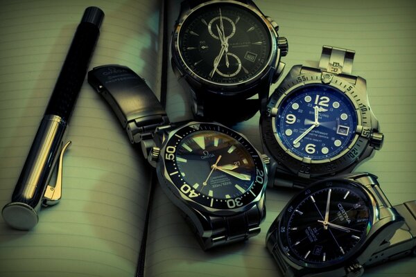 Several wristwatches are lying on an open notebook