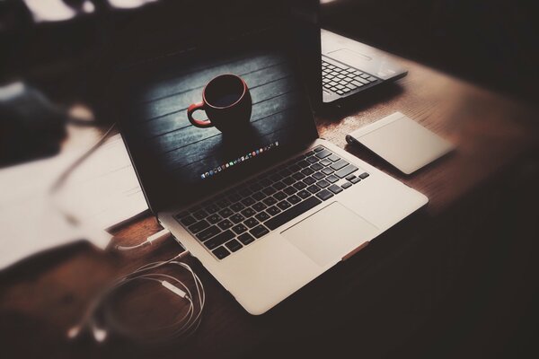 Ordinateur portable avec des écouteurs sur la table avec l image sur l écran de la tasse