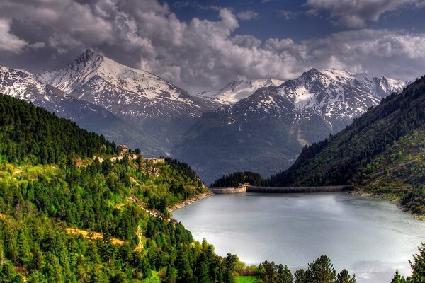 Ein ruhiger Waldsee und Berge in den Wolken