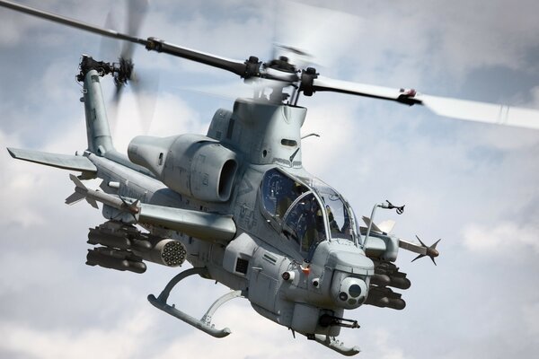 A gray helicopter flying in the clouds