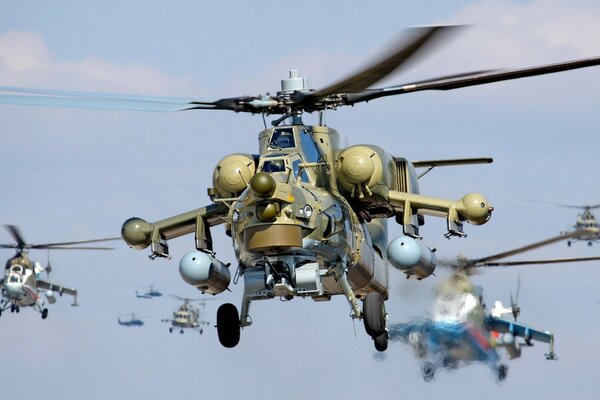 Several helicopters are flying in combat order across the clear sky