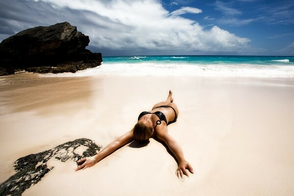 Femme bronzante sur le sable blanc