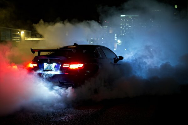 Coche con humo y luces en el fondo de las casas