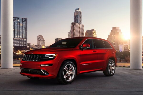 Bright red jeep on the background of urban high-rise buildings