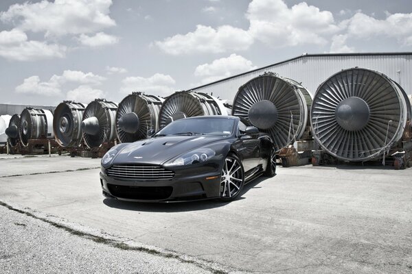 Aston Martin noir sur fond de turbines d avions