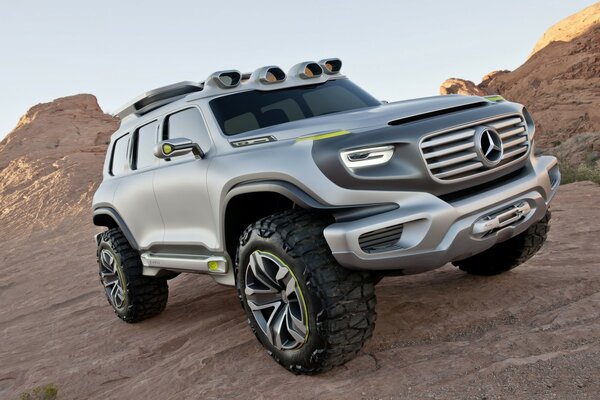 A silver-colored SUV on a background of sandy rocks