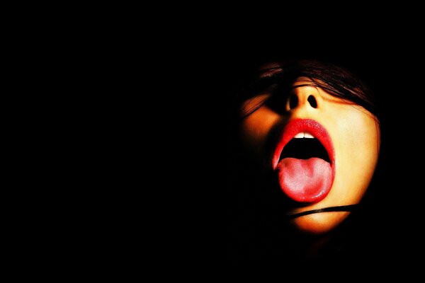 Girl s mouth open with tongue on black background