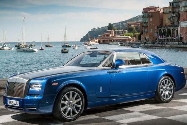 Blue car in front of boats and the sea