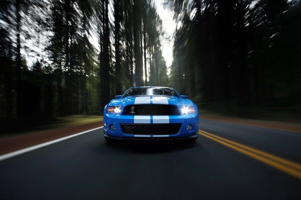 A blue Ford Mustang is flying down the road