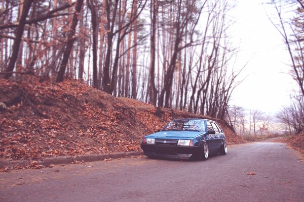 A blue car is moving on the road