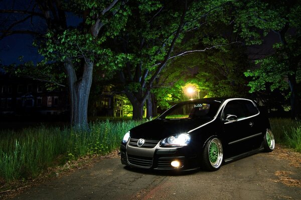 Black Volkswagen Golf hatchback in the night forest