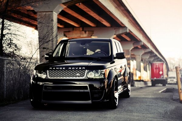 Black Rang Rover on stylish wheels under the bridge