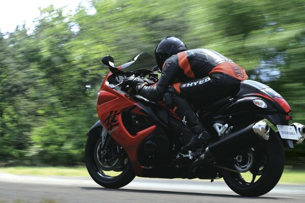 Moto deportiva con conductor a la velocidad en el fondo del bosque