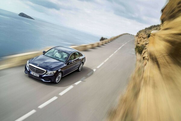 Dark blue mercedes benz on the river coast in the mountains