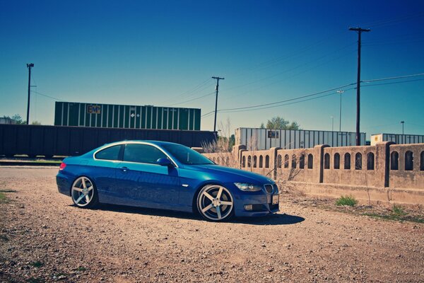 BMW azul al lado del tren y la cerca